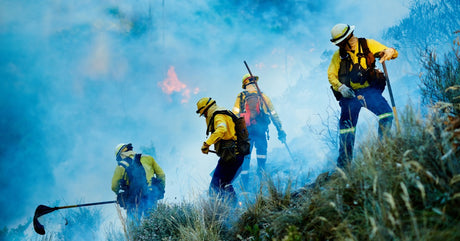 Wildland fire fighters combatting a spreading blaze with various tools.
